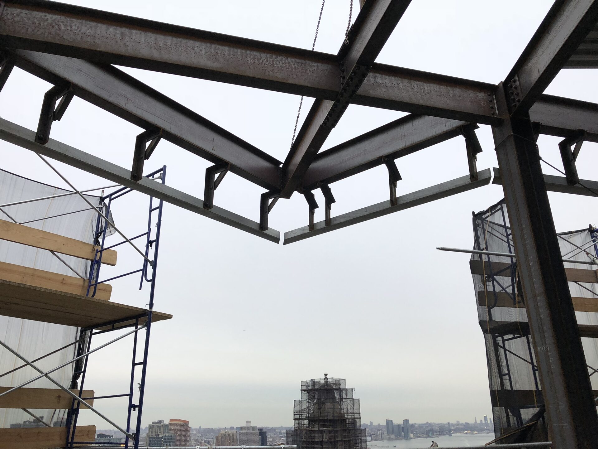 The Oriana — new structural steel framing at the top of the tower with the East River and Queens skyline beyond